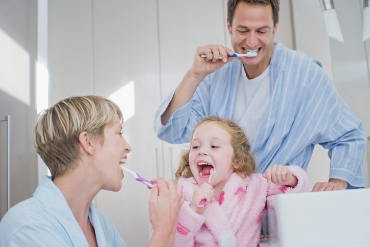 Family brushing teeth in bathroom