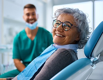 Woman with black glasses smiling in treatment chair