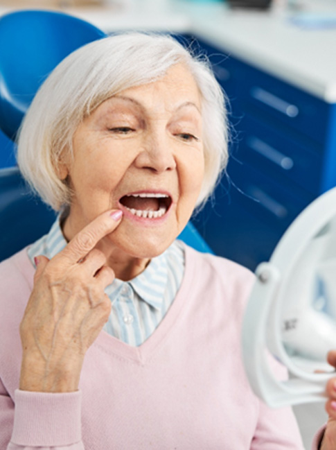 A woman looking in the mirror at her dentures