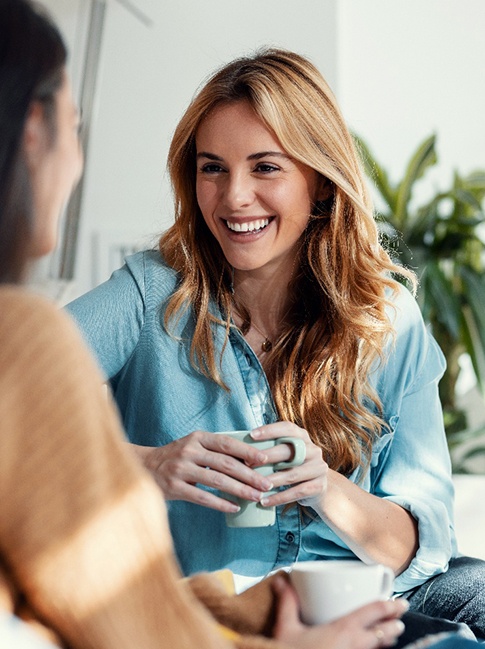 Woman smiling while drinking coffee with friend