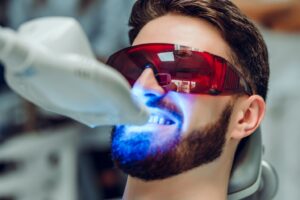 Patient having his teeth professionally whitened at dentist’s office.